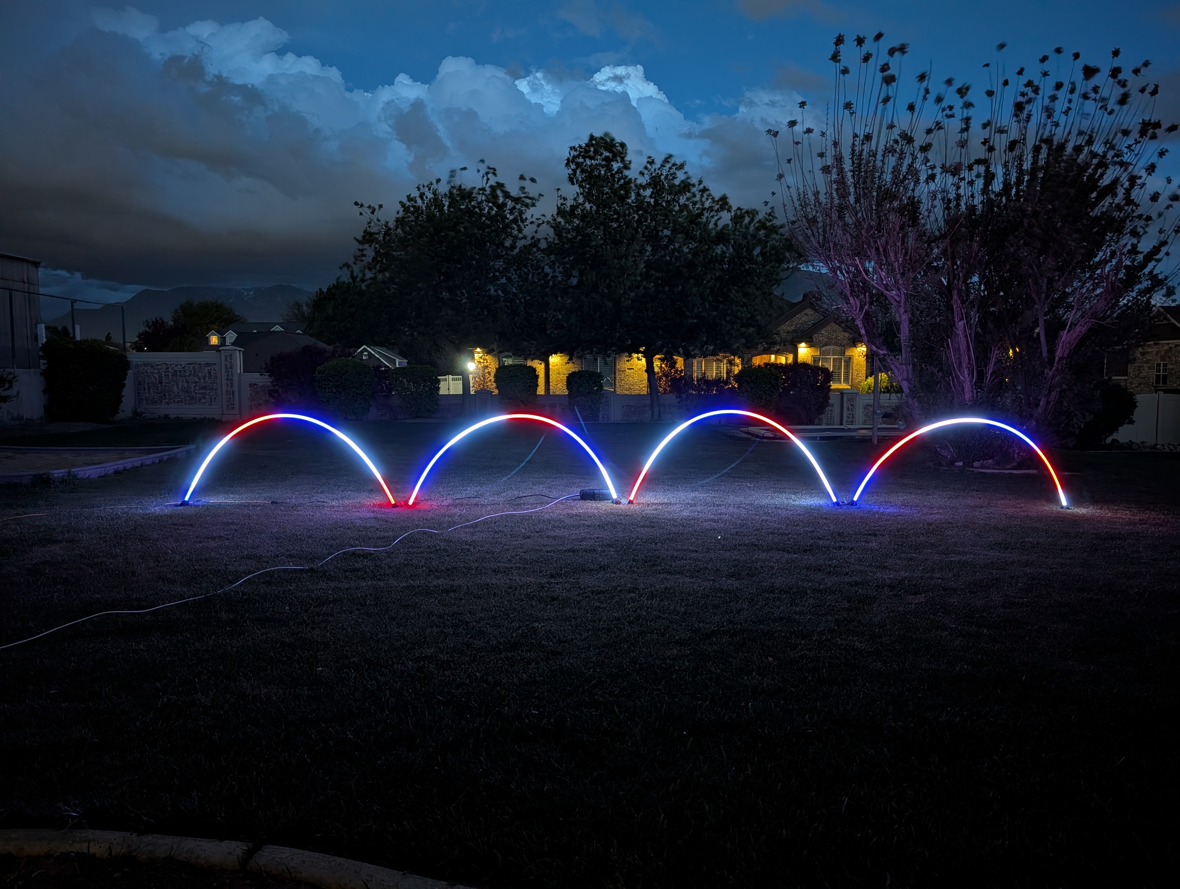 AFTERGLO arches lit at night, multi-color palette across the front yard