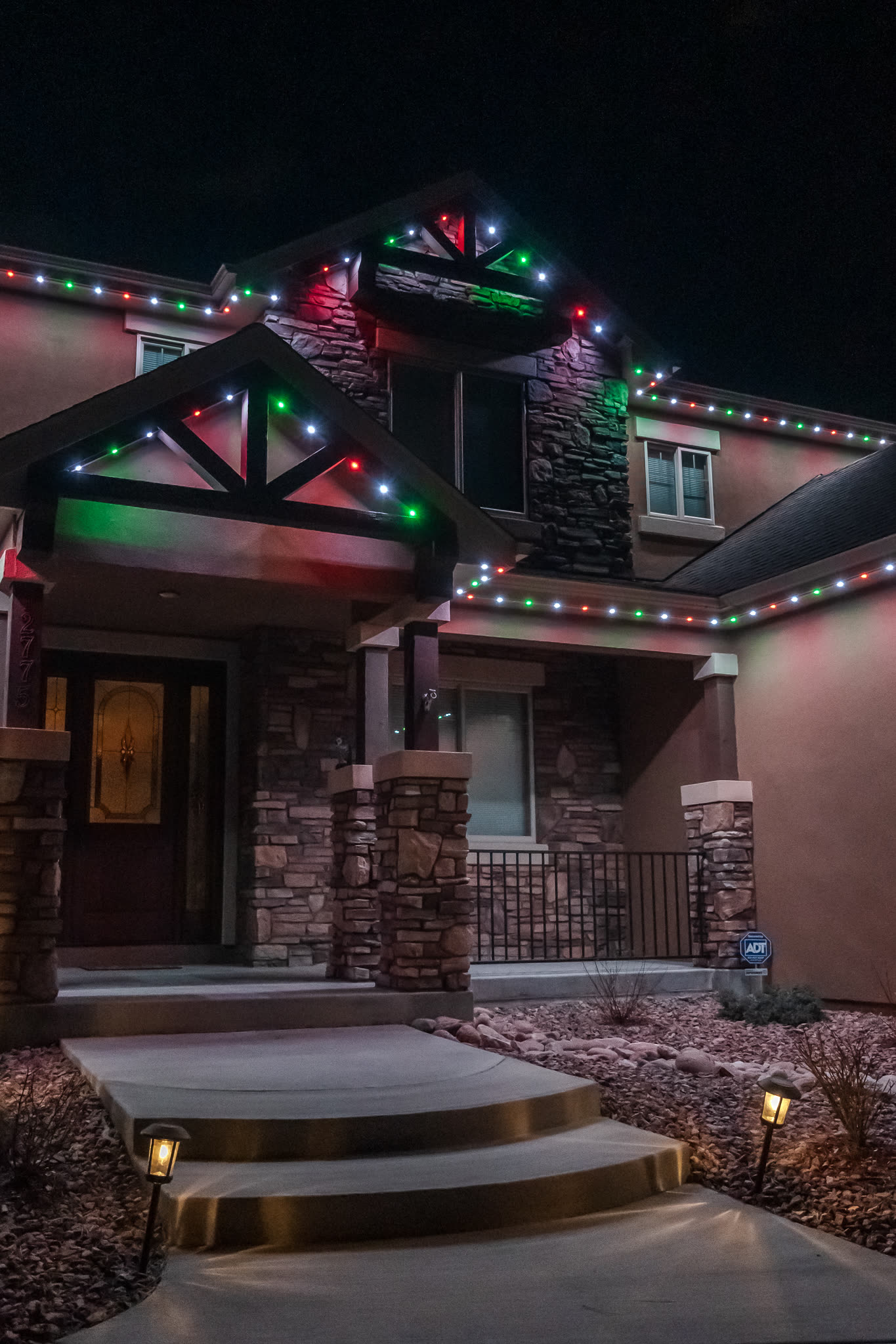 Home with red, green, and white permanent LED roofline lighting for Christmas