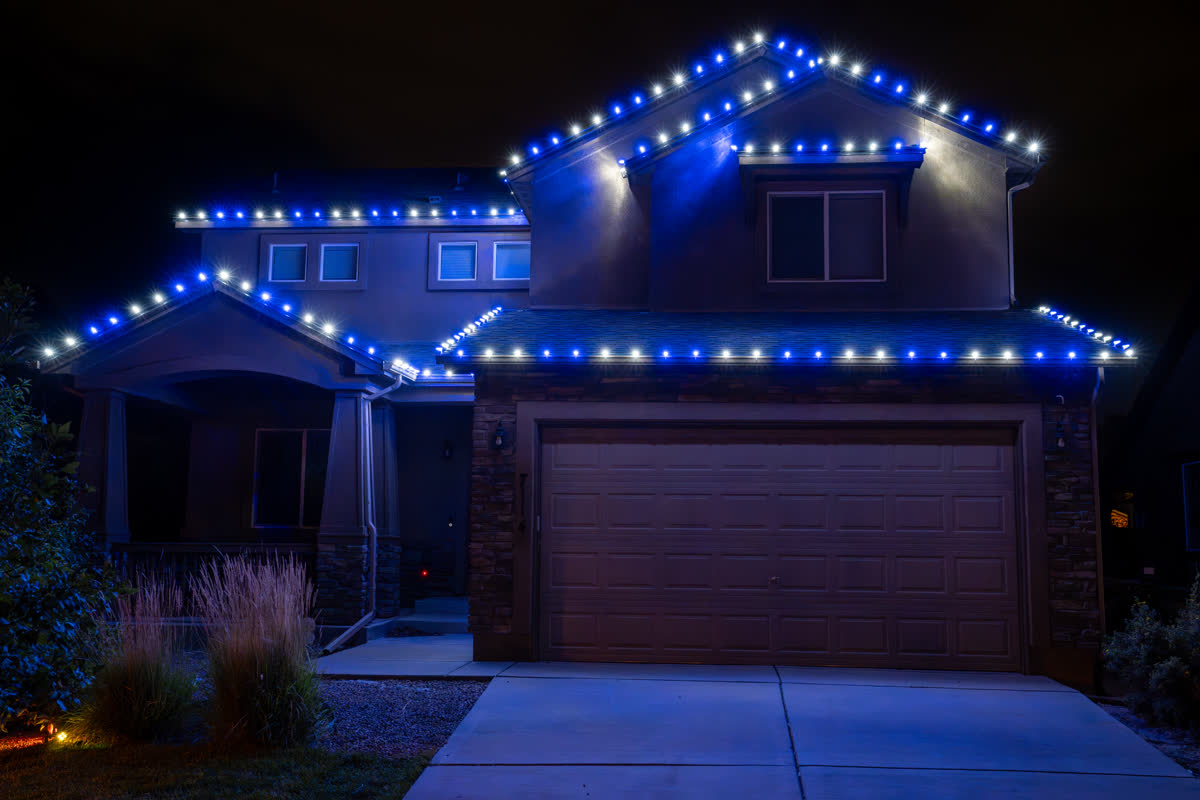 Home with blue and white Christmas string lights on the roofline
