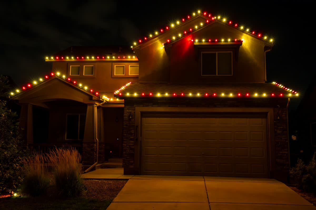Home with red and gold Christmas string lights on the roofline