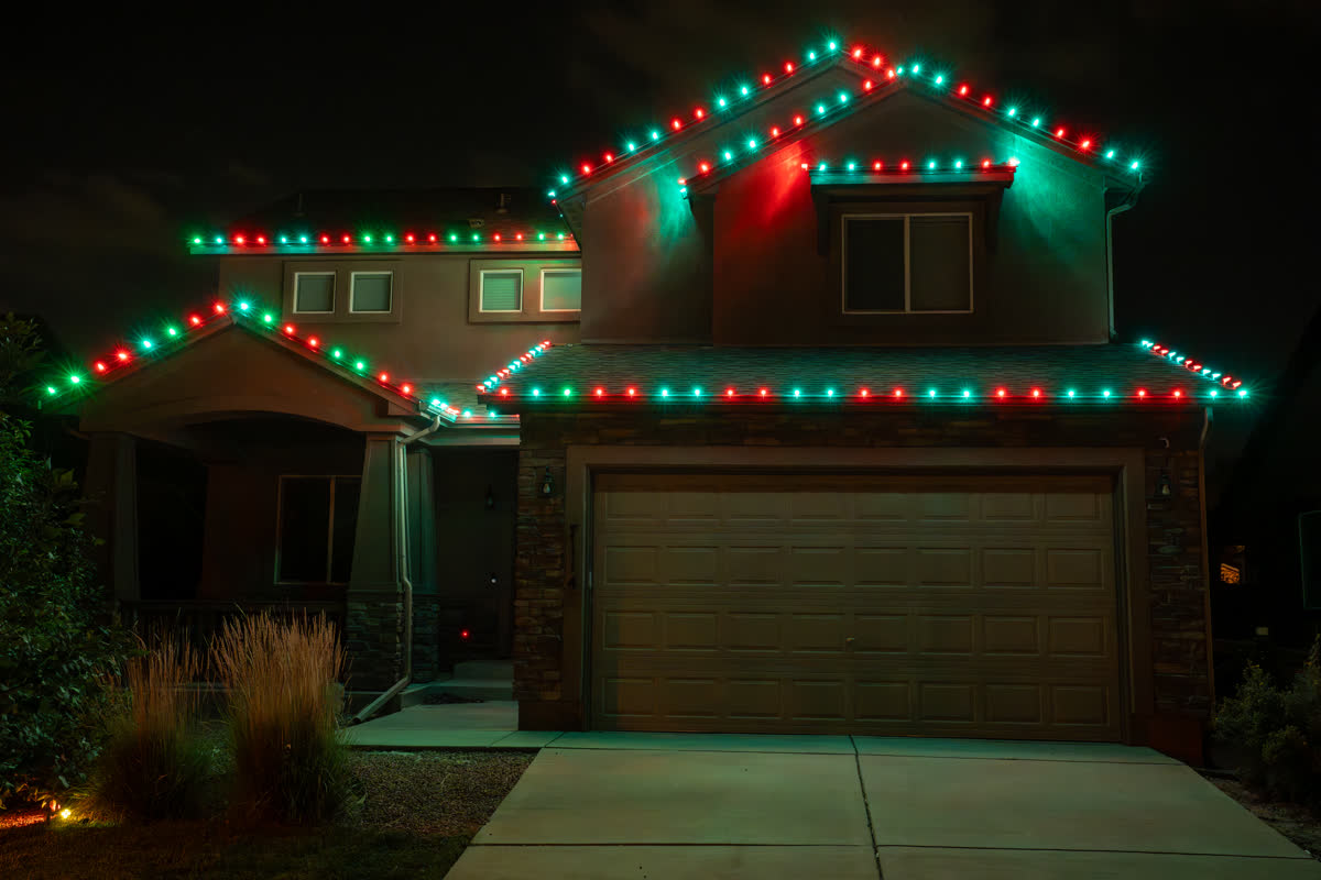 Home with red and green Christmas string lights on the roofline