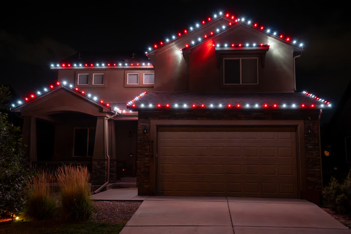 Home with red and white Christmas string lights on the roofline