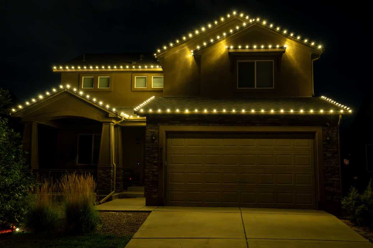 Home with classic warm white Christmas string lights on the roofline